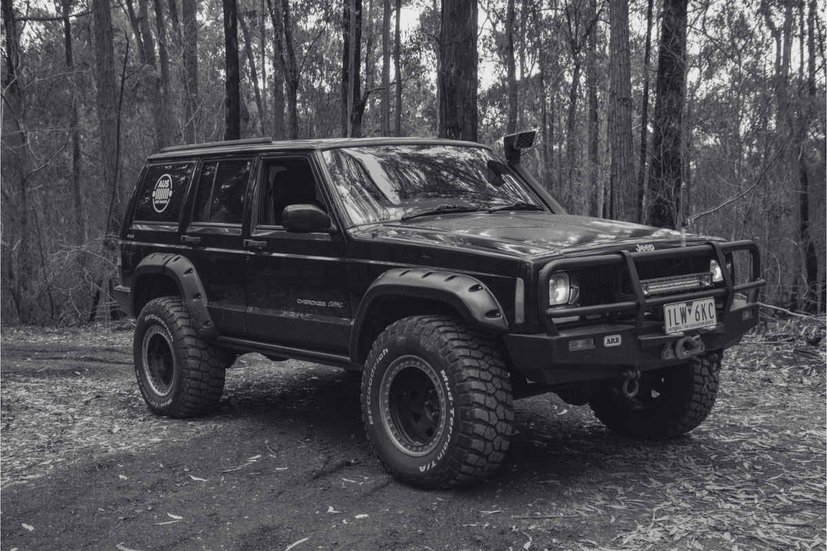 Black lifted Jeep Cherokee XJ with Aus Jeep Spares logo on a bush track